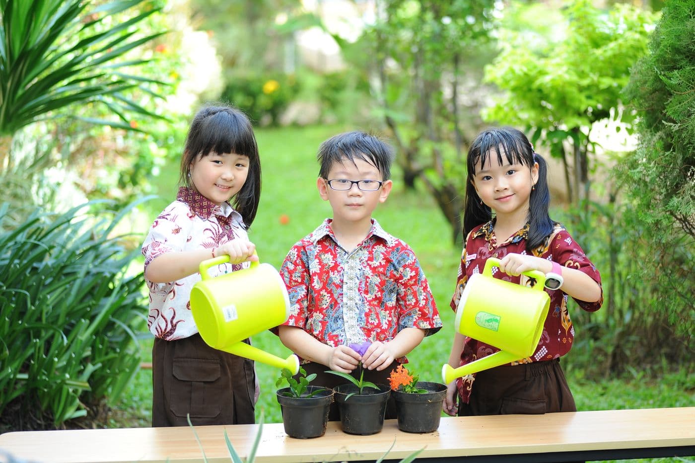 Kids watering plants together in a garden, practicing a troop task